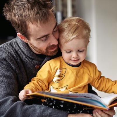 A father reads to their child from a storybook